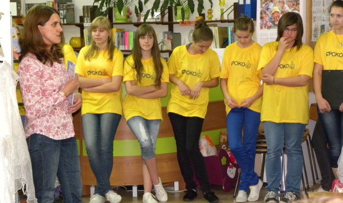 Uczestnicy projektu w żółtych koszulkach z pracownikiem biblioteki