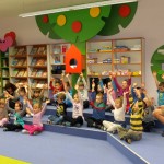 Dzieci siedzą po turecku i podnoszą ręce do góry