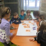 Dzieci zgromadzeni wokół stołu wykonują komiks na dużym arkuszu papieru