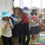Dzieci w słomianych kapeluszach czytają laurki