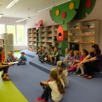 Dzieci siedzą i słuchają bibliotekarki