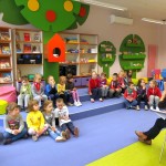 Dzieci siedzą i słuchają bibliotekarki