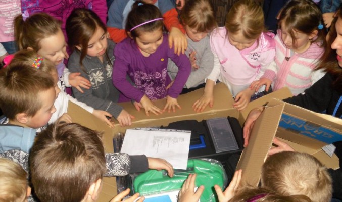 Dzieci otwierają paczki z przyborami badawczymi