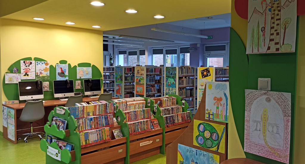 Wnętrze biblioteki z wyposażeniem meblowym, które oklejono pracami konkursowymi