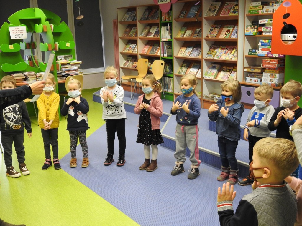 Dzieci stojąć w półkolu pokazują rękami gesty w trakcie zabawy