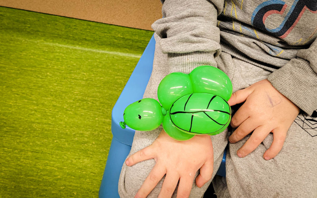 Zielony żółwik stworzony z balonu do modelowania założony na nadgarstek dziecka