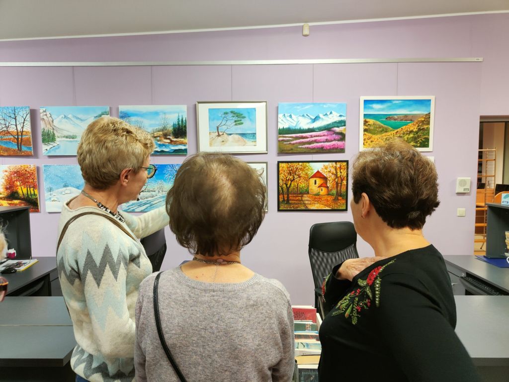 widok od tyłu na trzy kobiety patrzące na obrazy wiszące na ścianie